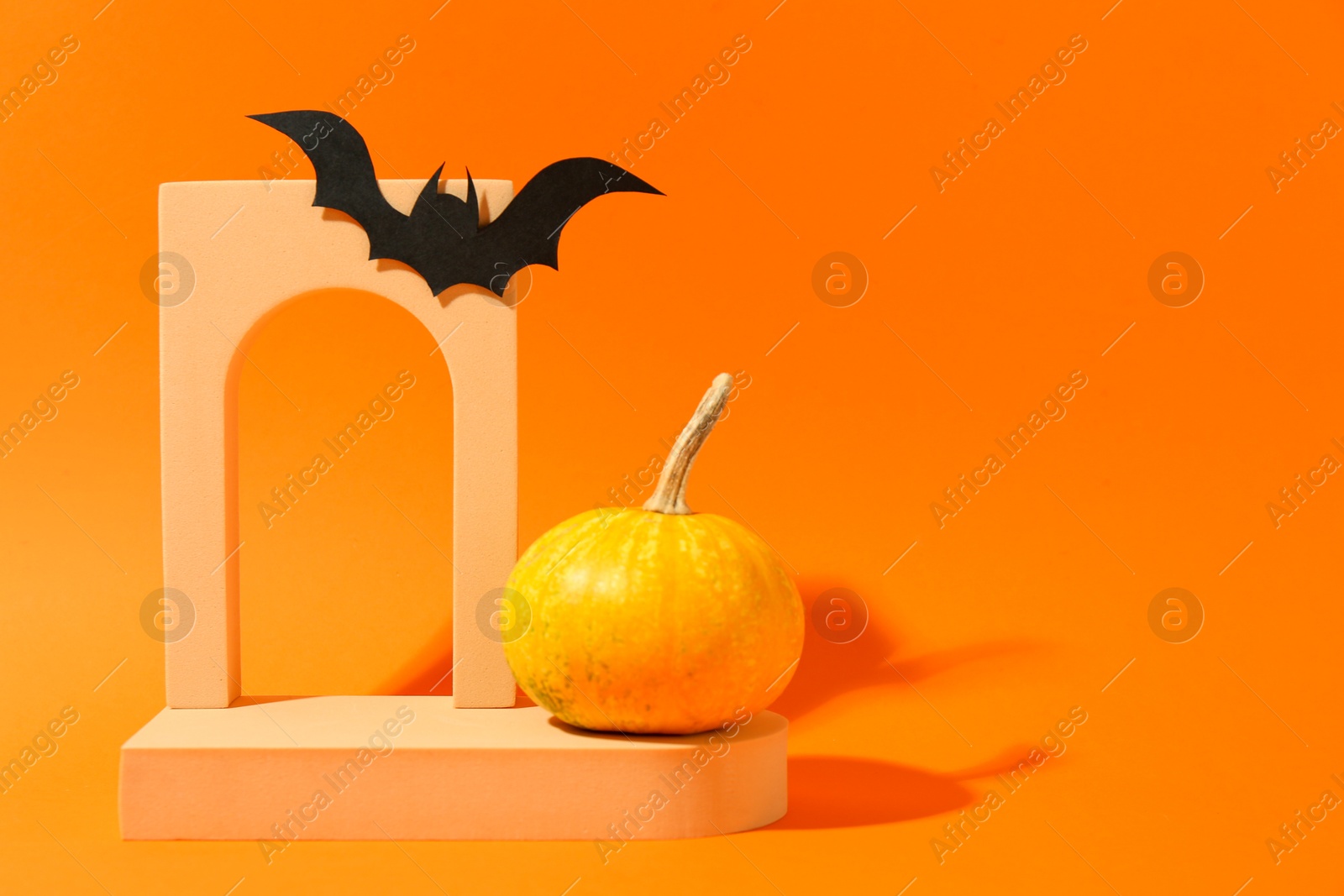 Photo of Halloween celebration. Black paper bat, pumpkin and geometric figures on orange background, space for text