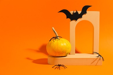 Photo of Halloween celebration. Black paper bat, spiders, pumpkin and geometric figures on orange background, space for text