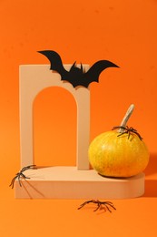 Photo of Halloween celebration. Black paper bat, spiders, pumpkin and geometric figures on orange background