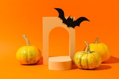 Photo of Halloween celebration. Black paper bat, pumpkins and geometric figures on orange background