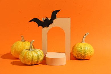 Photo of Halloween celebration. Black paper bat, pumpkins and geometric figures on orange background