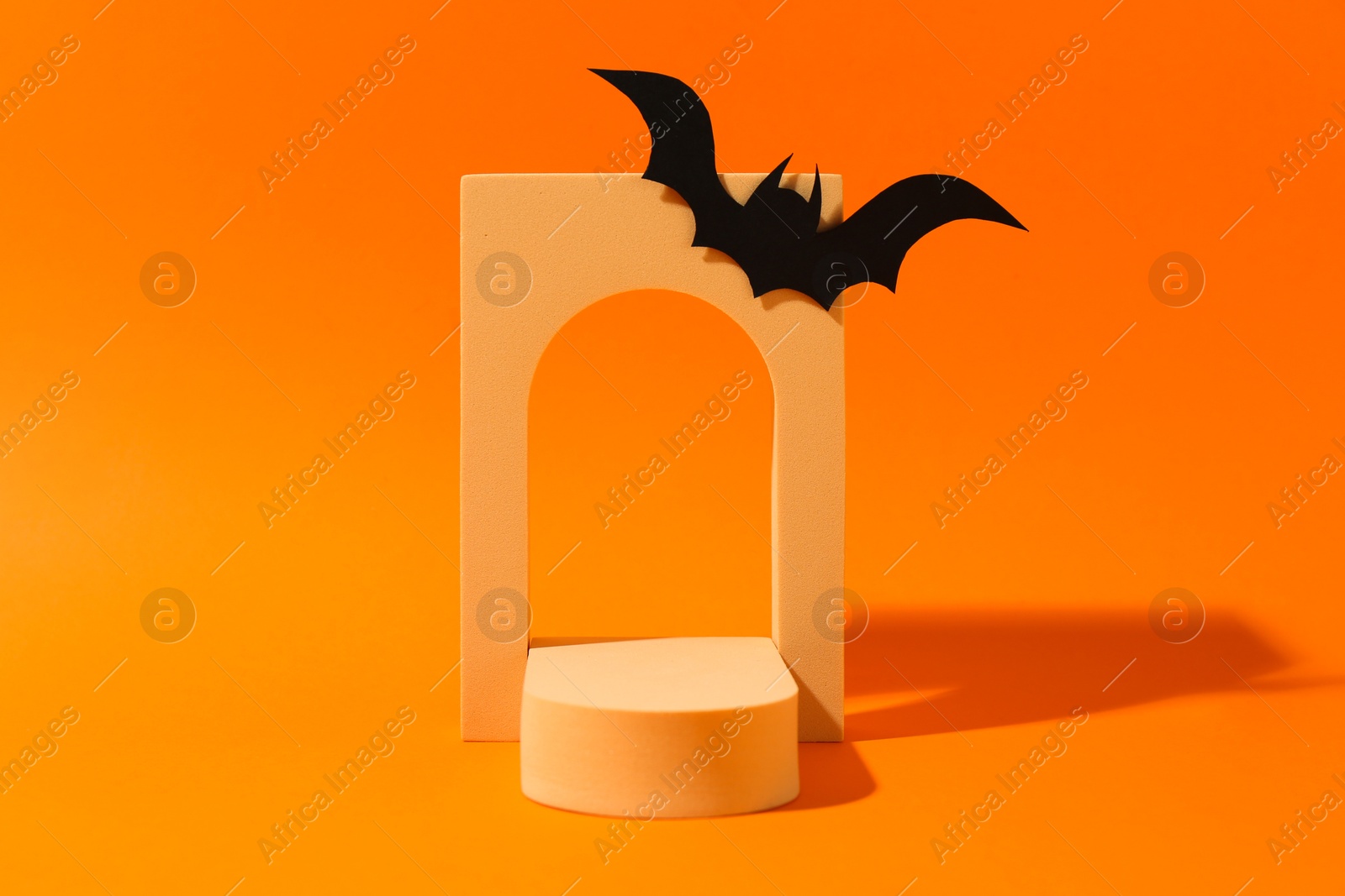 Photo of Halloween celebration. Black paper bat and geometric figures on orange background