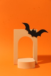 Photo of Halloween celebration. Black paper bat and geometric figures on orange background