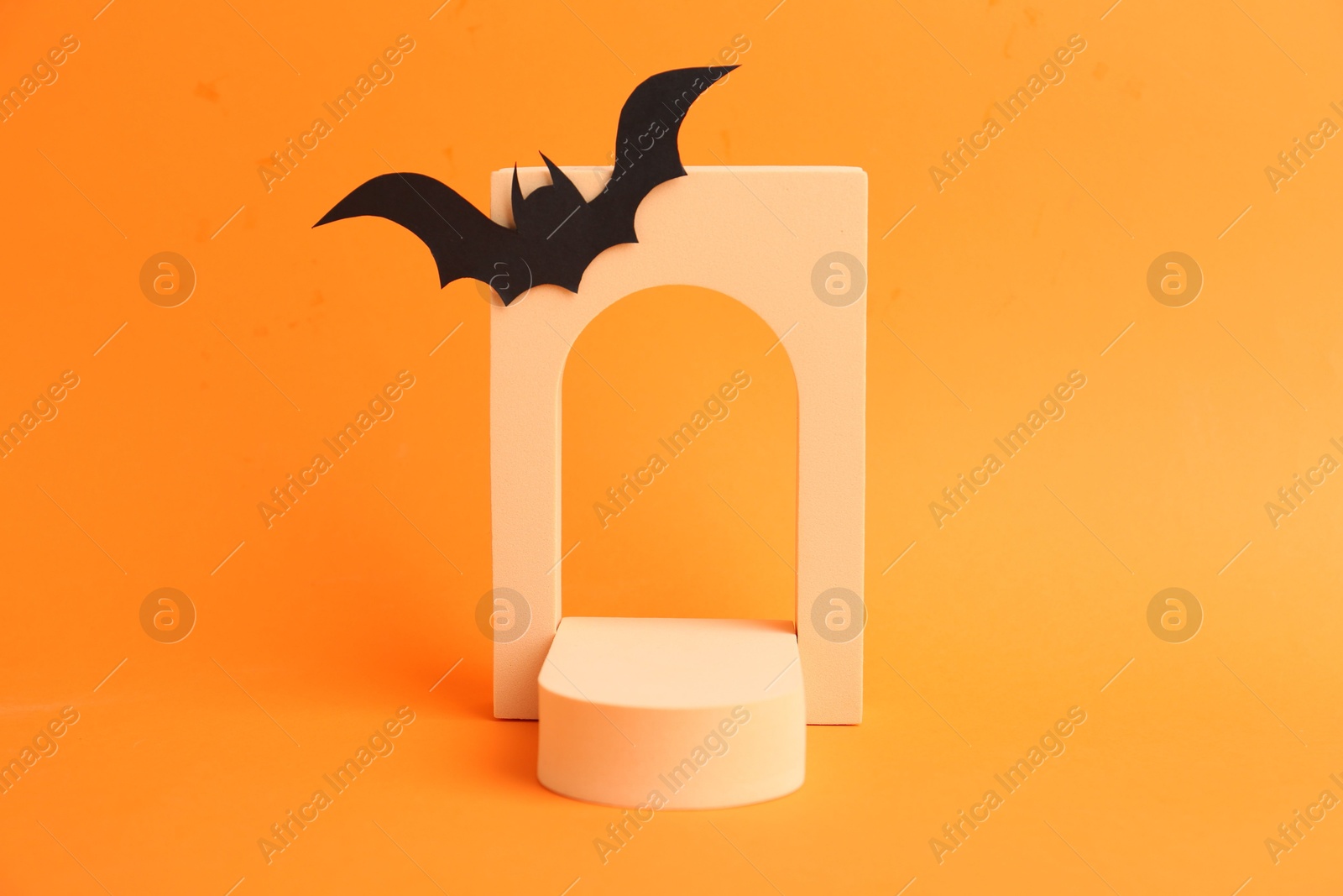 Photo of Halloween celebration. Black paper bat and geometric figures on orange background