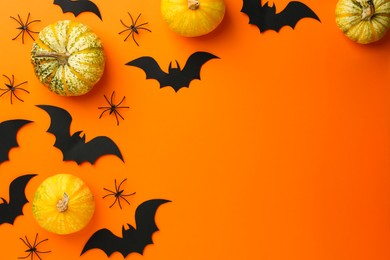 Photo of Halloween celebration. Black paper bats, spiders and pumpkins on orange background, flat lay. Space for text