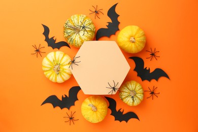 Photo of Halloween celebration. Black paper bats, spiders, pumpkins and podium on orange background, flat lay