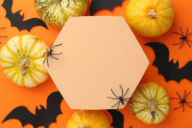 Photo of Halloween celebration. Black paper bats, spiders, pumpkins and podium on orange background, flat lay