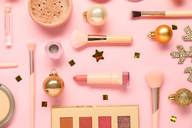 Photo of Different makeup brushes, decorative cosmetics and Christmas decor on pink background, flat lay