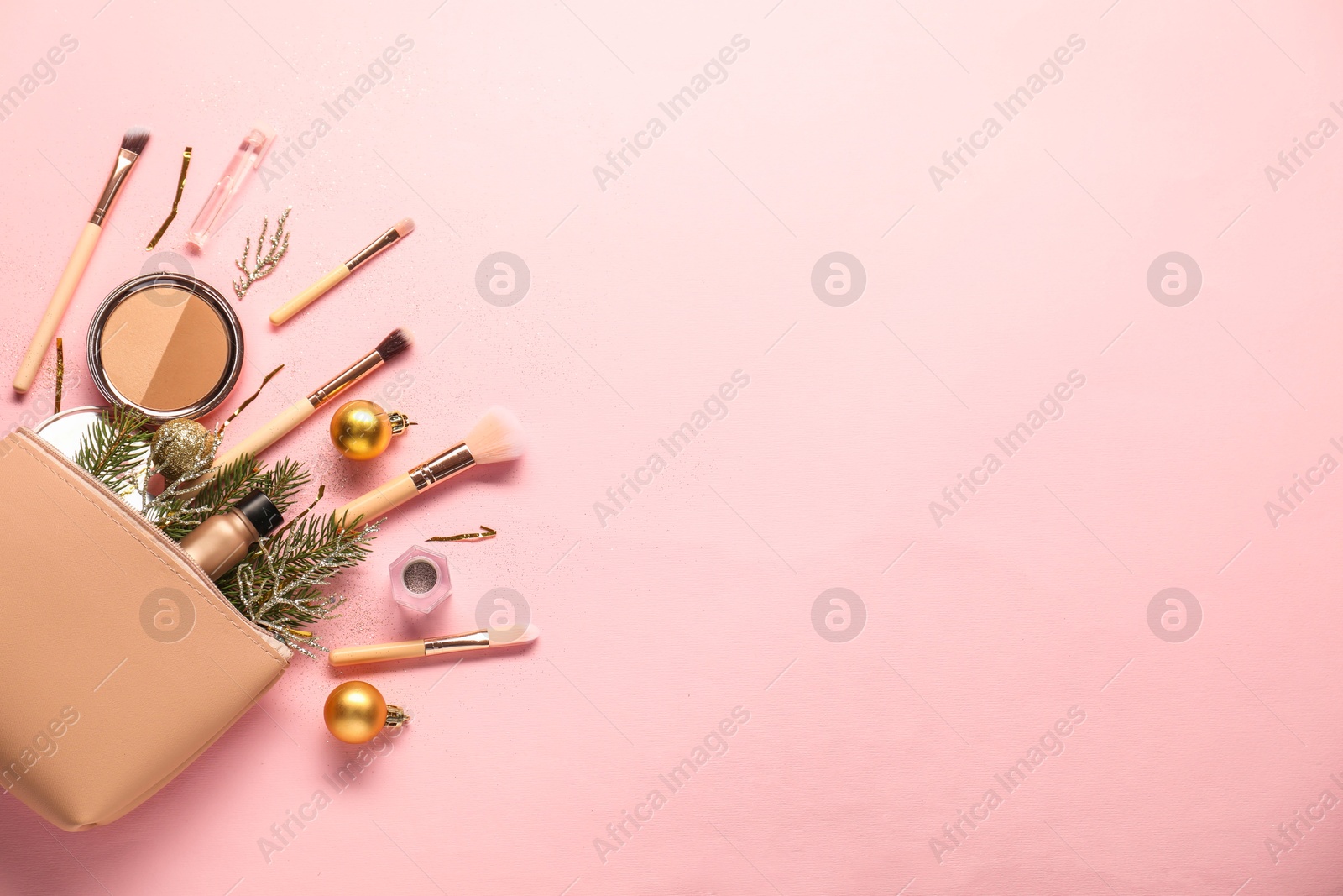 Photo of Different makeup brushes, decorative cosmetics and Christmas decor on pink background, flat lay. Space for text