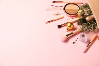 Photo of Different makeup brushes, decorative cosmetics and Christmas decor on pink background. Space for text