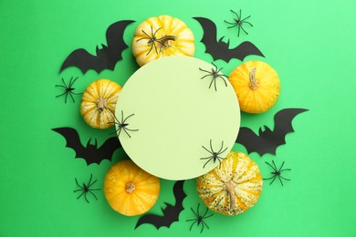 Photo of Halloween celebration. Black paper bats, spiders, pumpkins and podium on green background, flat lay