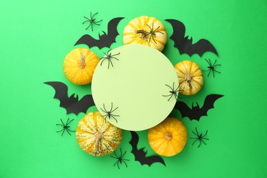 Photo of Halloween celebration. Black paper bats, spiders, pumpkins and podium on green background, flat lay