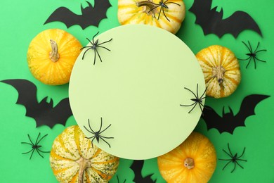 Halloween celebration. Black paper bats, spiders, pumpkins and podium on green background, flat lay