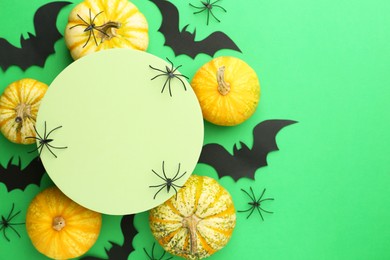 Photo of Halloween celebration. Black paper bats, spiders, pumpkins and podium on green background, flat lay