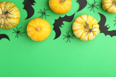 Photo of Halloween celebration. Black paper bats, spiders and pumpkins on green background, flat lay. Space for text