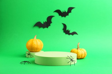 Photo of Halloween celebration. Black paper bats, spiders, pumpkins and podiums on green background