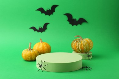 Photo of Halloween celebration. Black paper bats, spiders, pumpkins and podiums on green background