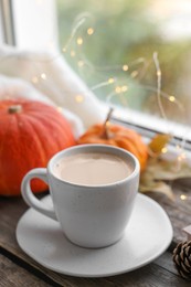 Photo of Cup of coffee and pumpkins on window sill. Autumn atmosphere