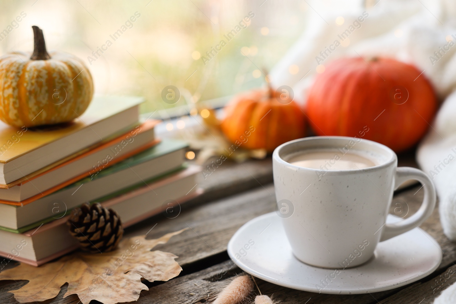 Photo of Cup of coffee, books and autumn decor on wooden table, closeup