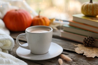 Photo of Cup of coffee, books and autumn decor on wooden table, closeup