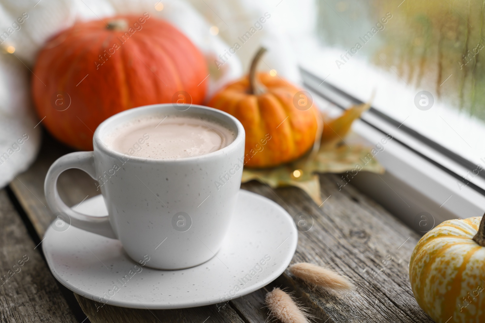 Photo of Cup of coffee and autumn decor on window sill, closeup