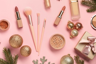 Photo of Different makeup brushes, decorative cosmetics and Christmas decor on pink background, flat lay