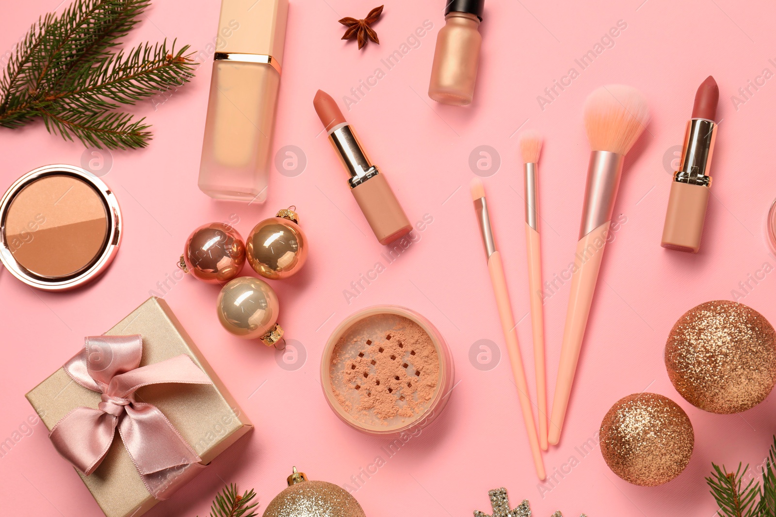 Photo of Different makeup brushes, decorative cosmetics and Christmas decor on pink background, flat lay