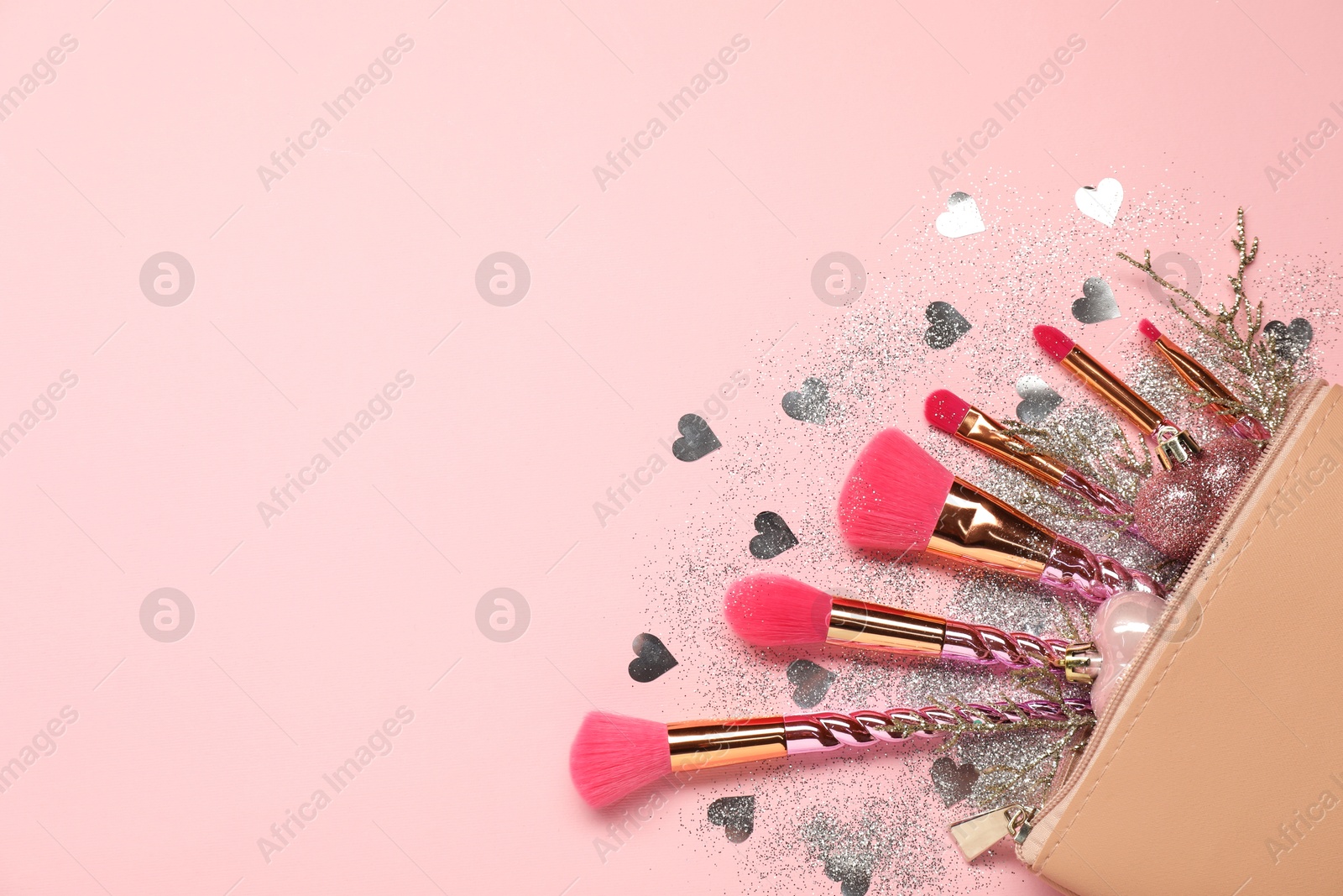 Photo of Cosmetic bag with makeup brushes and Christmas decor on pink background, top view. Space for text