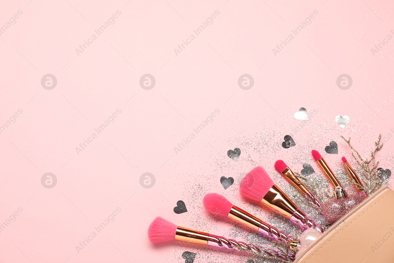 Photo of Cosmetic bag with makeup brushes and Christmas decor on pink background, top view. Space for text