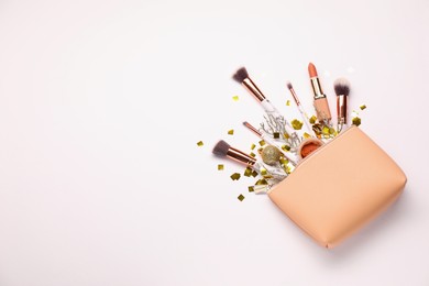 Photo of Cosmetic bag with makeup brushes, decorative cosmetics and Christmas decor on white background, top view. Space for text