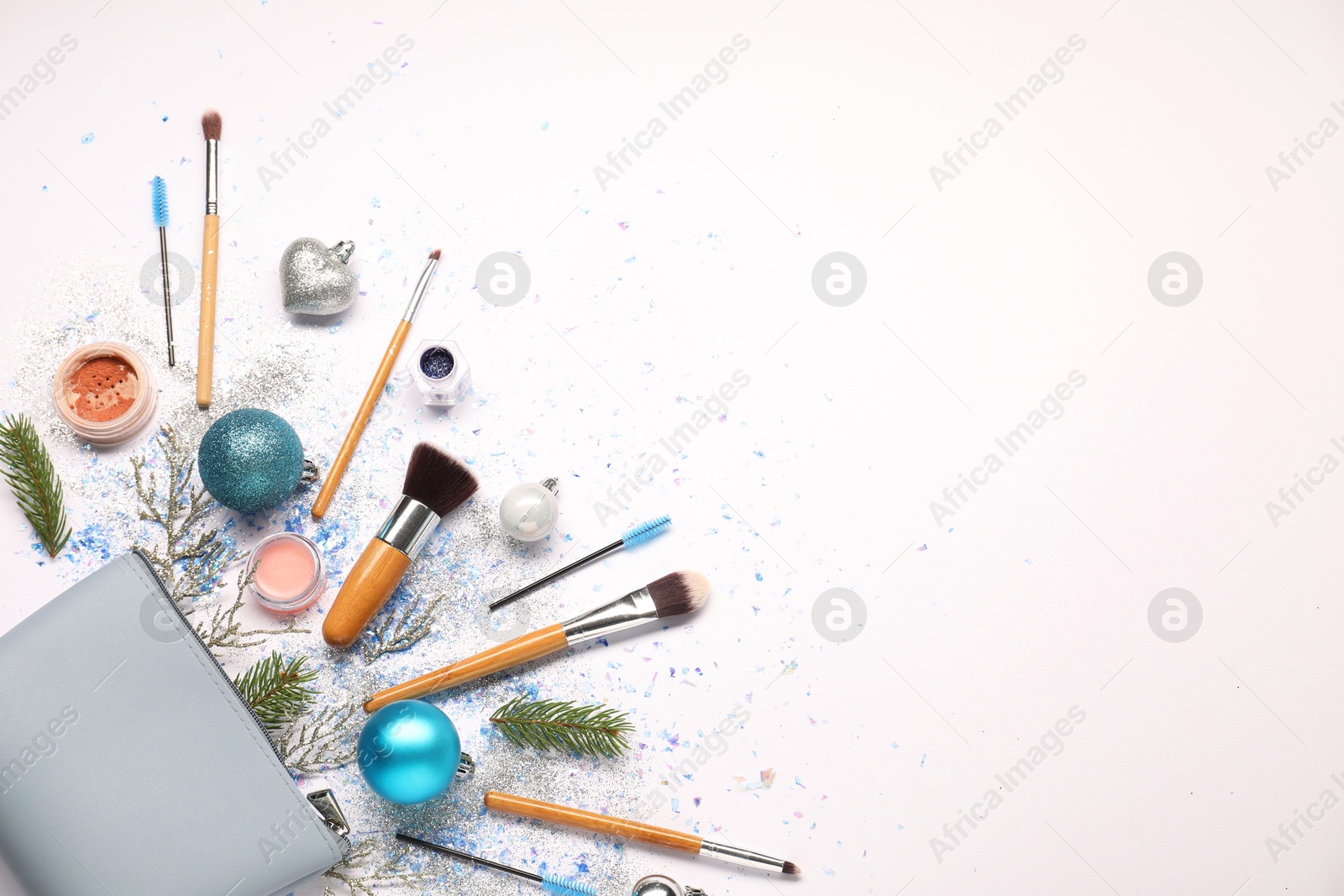 Photo of Cosmetic bag, makeup brushes, decorative cosmetics and Christmas decor on white background, flat lay. Space for text