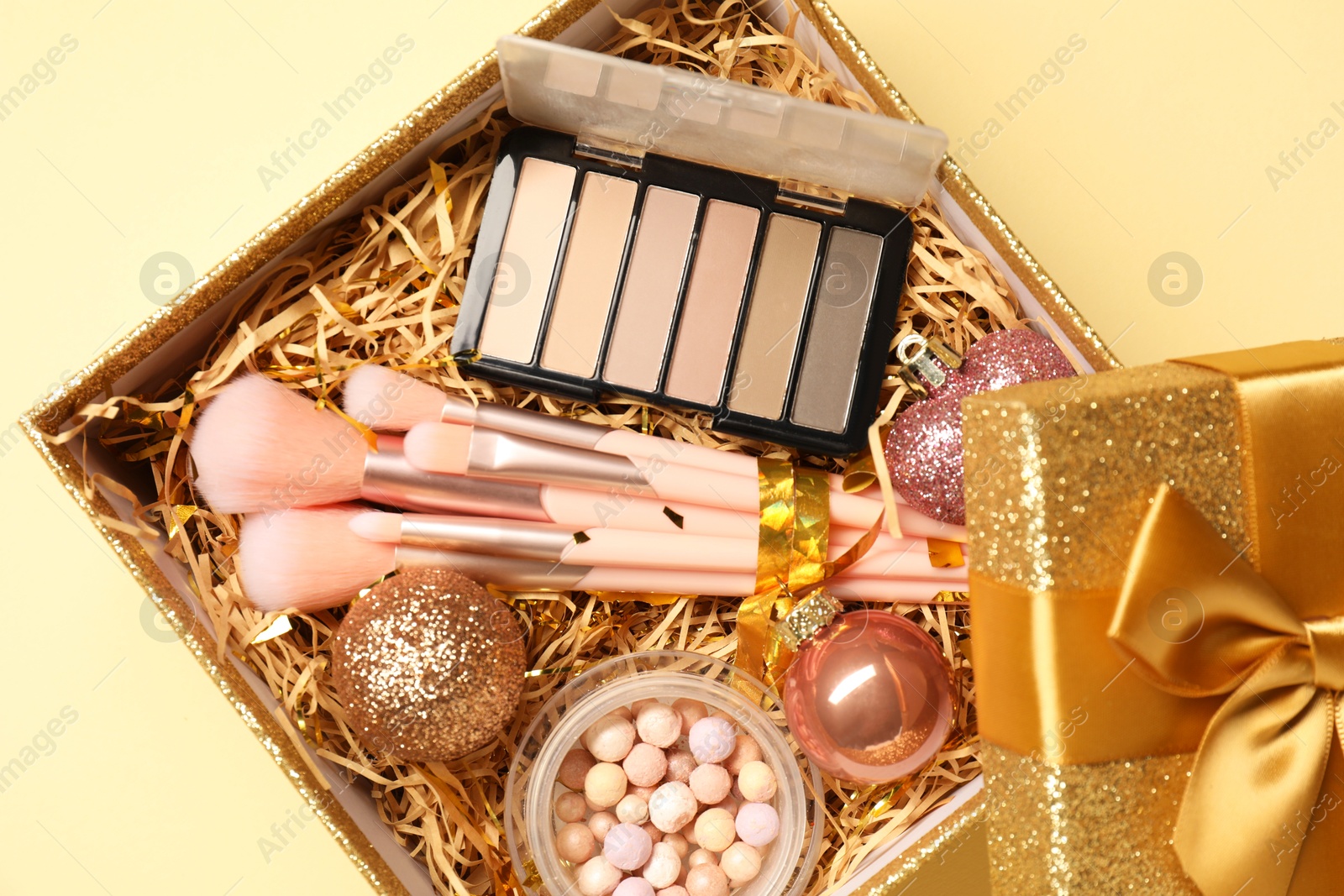 Photo of Makeup brushes, blush and Christmas decor in box on yellow background, top view