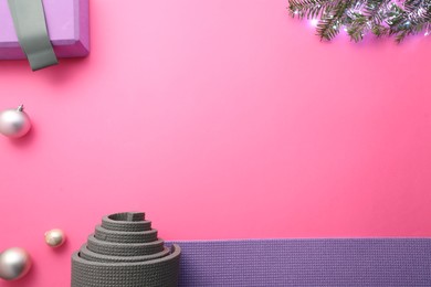 Photo of Yoga mat, block, fir branches and Christmas decor on pink background, flat lay. Space for text