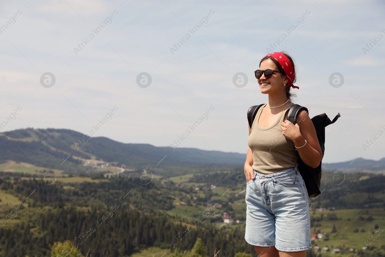 Photo of Smiling tourist with backpack in mountains. Space for text