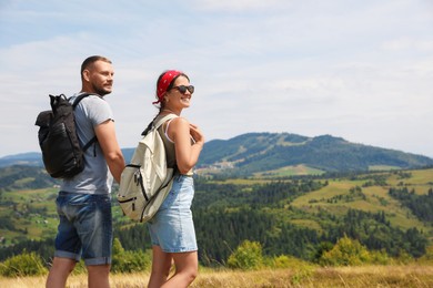 Happy couple with backpacks enjoying picturesque landscape, space for text. Active tourism