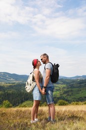 Photo of Couple with backpacks holding hands outdoors. Active tourism