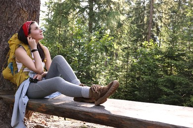 Photo of Young hiker sitting on wooden bench in forest