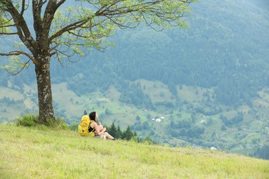 Photo of Young hiker with backpack in mountains, space for text