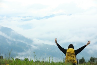 Photo of Young hiker with backpack in mountains, back view. Space for text