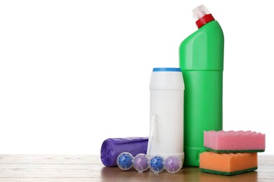 Photo of Different toilet cleaners, sponges and trash bags on wooden table against white background. Space for text