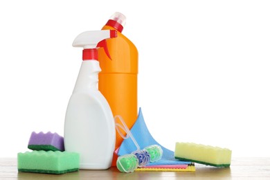 Photo of Different toilet cleaners, sponges and napkins on wooden table against white background