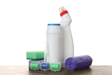 Photo of Different toilet cleaners, sponges and trash bags on wooden table against white background