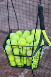 Photo of Tennis racket and balls in metal basket on court