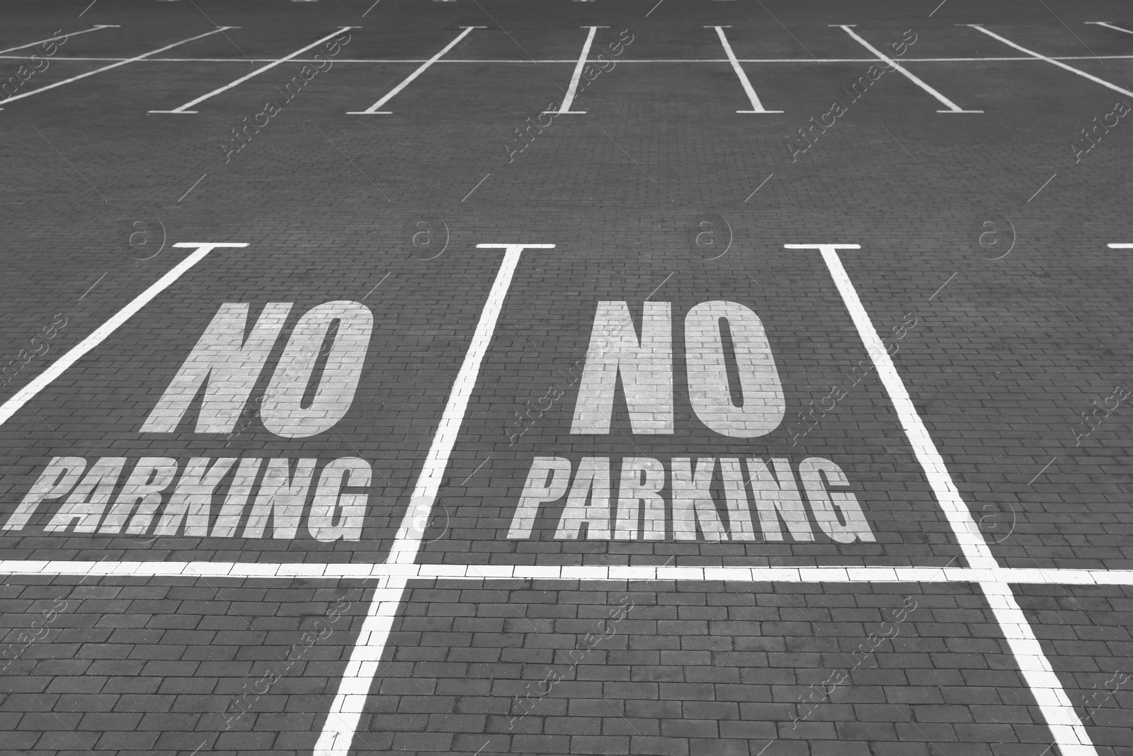 Image of Empty outdoor parking lot with painted markings on brick pavement