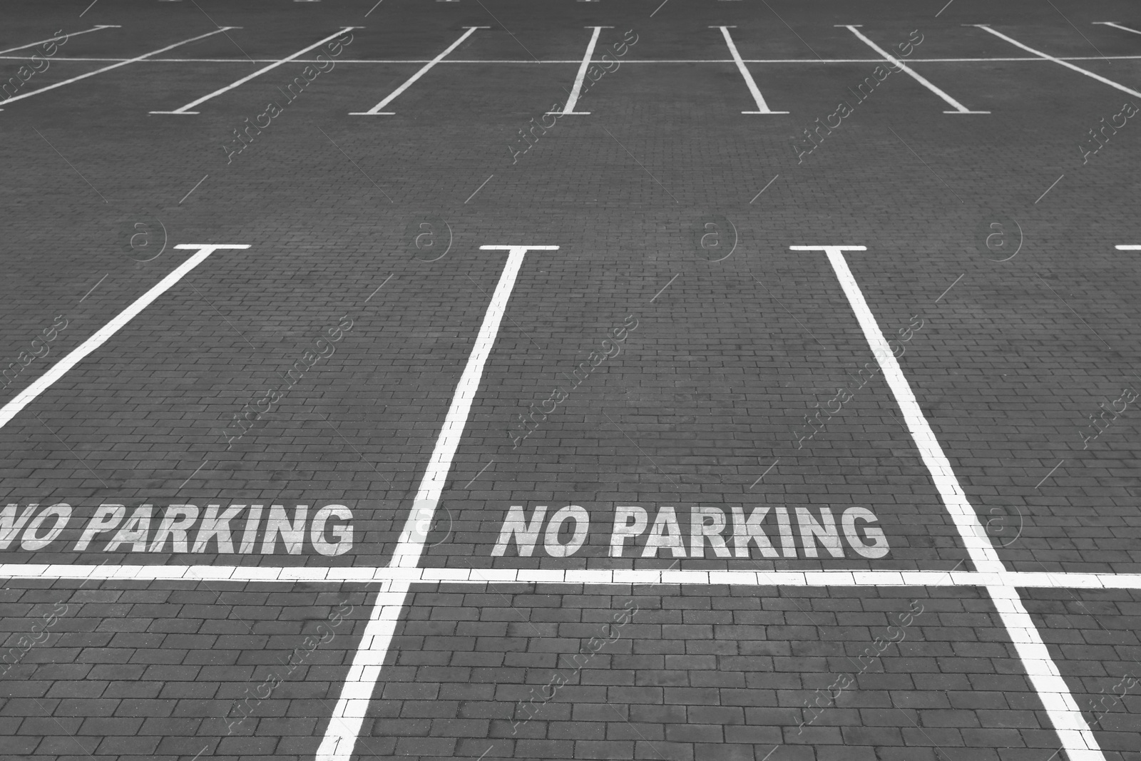 Image of Empty outdoor parking lot with painted markings on brick pavement