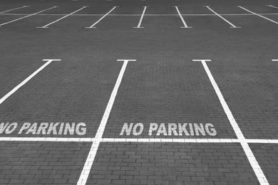 Image of Empty outdoor parking lot with painted markings on brick pavement