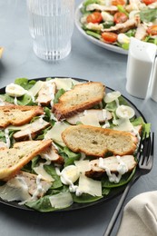 Photo of Delicious Caesar salad with chicken on grey textured table