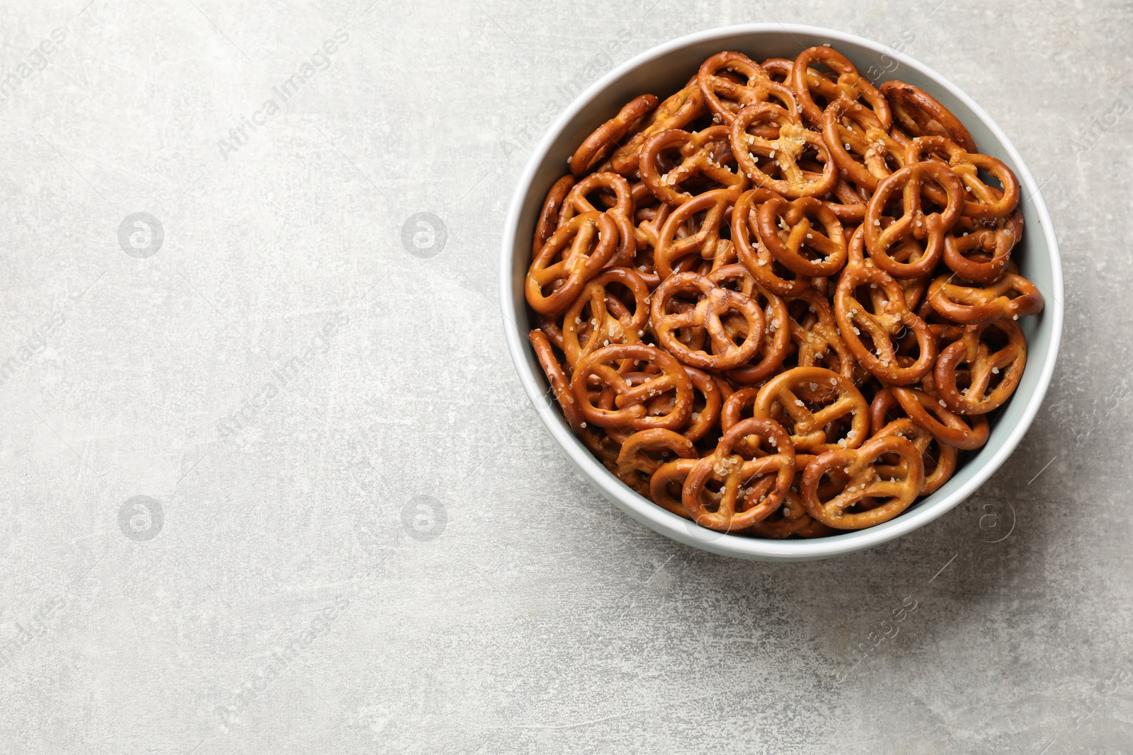 Photo of Delicious pretzel crackers on light table, top view. Space for text