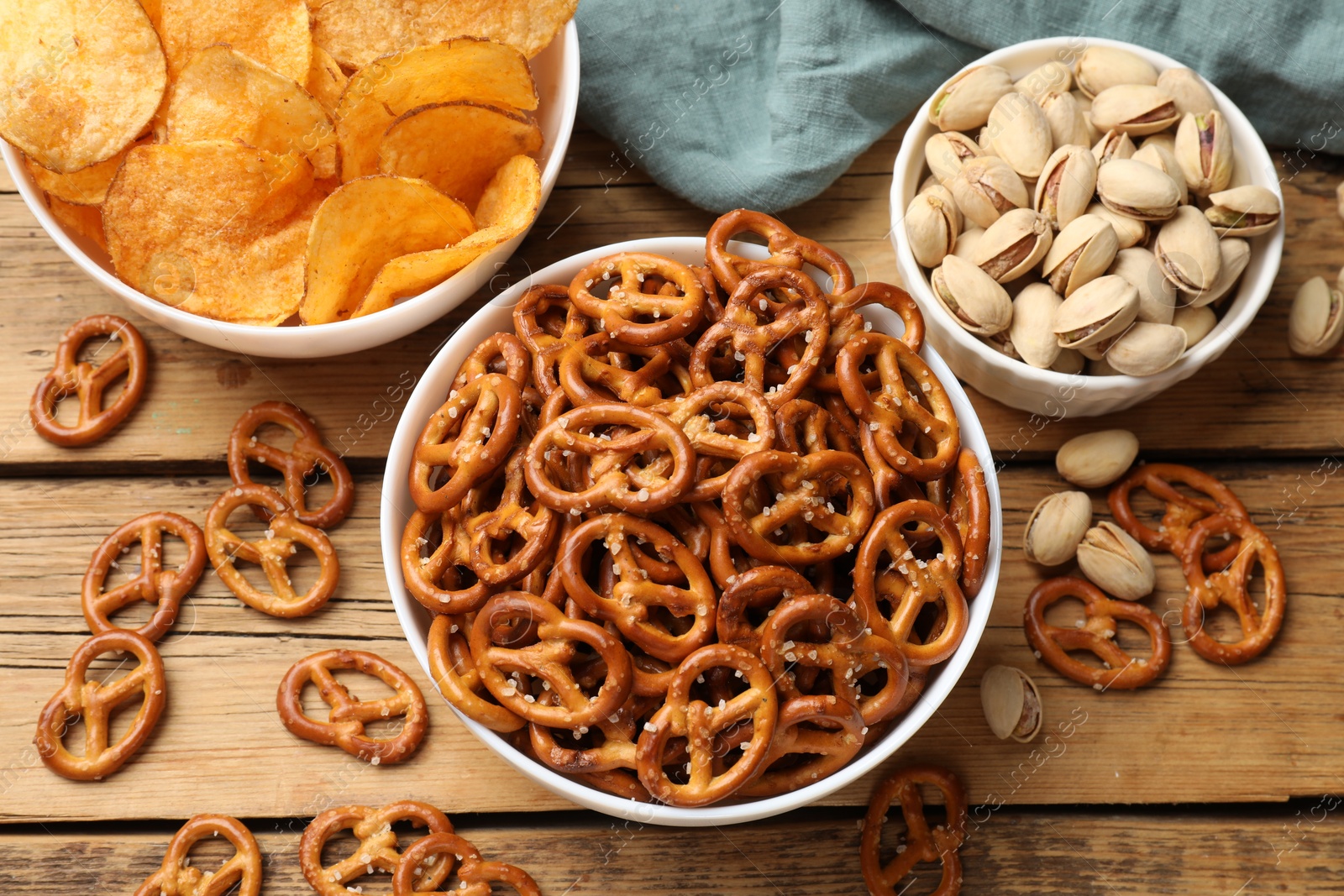 Photo of Delicious pretzel crackers and other snacks on wooden table, flat lay