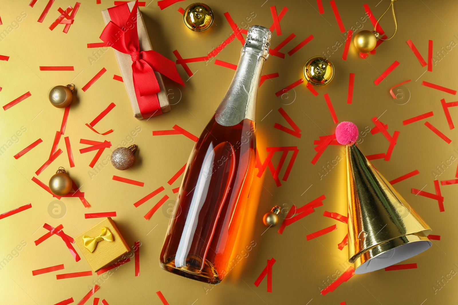 Photo of Flat lay composition with bottle of sparkling wine, confetti and other Christmas decor on beige background